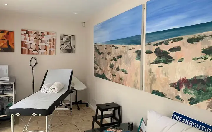 The TweakBoutique treatment room, with a treatment couch beneath two large paintings of Shoreham Beach