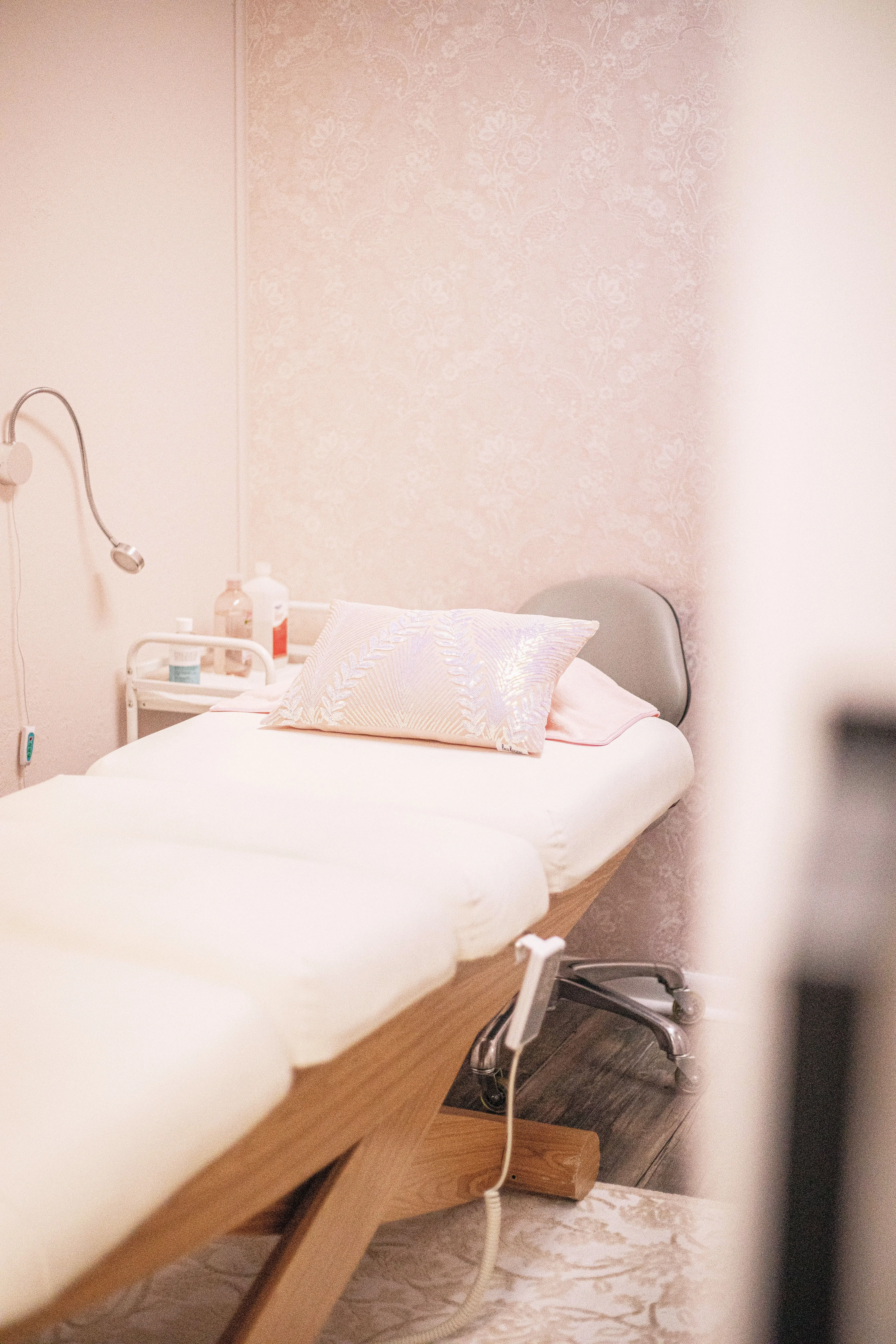 A quiet treatment room with a made-up couch in soft neutral tones