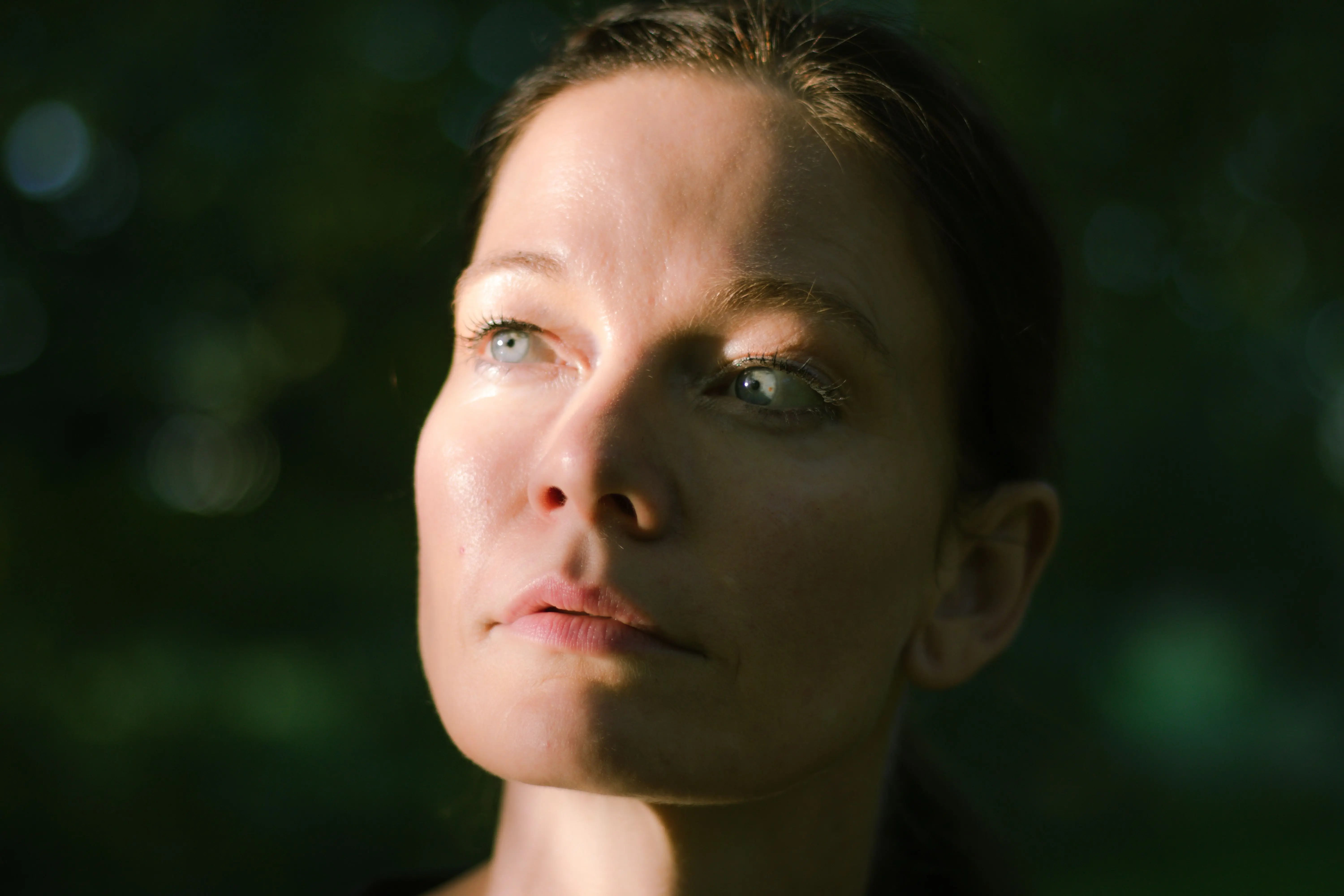 A woman in soft natural light looking upward in a quiet outdoor setting