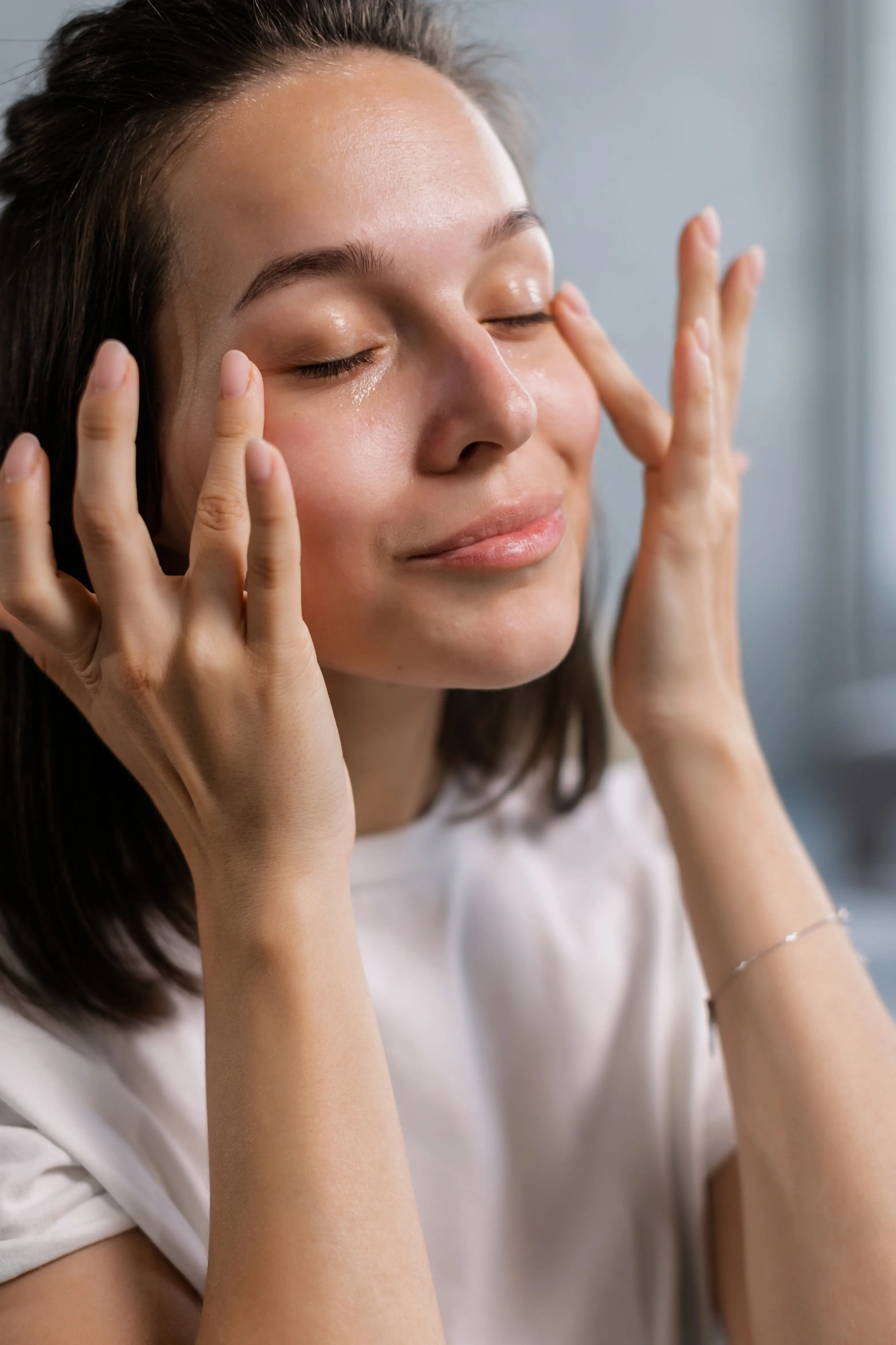 A woman with her eyes closed resting her fingertips lightly beside her eyes