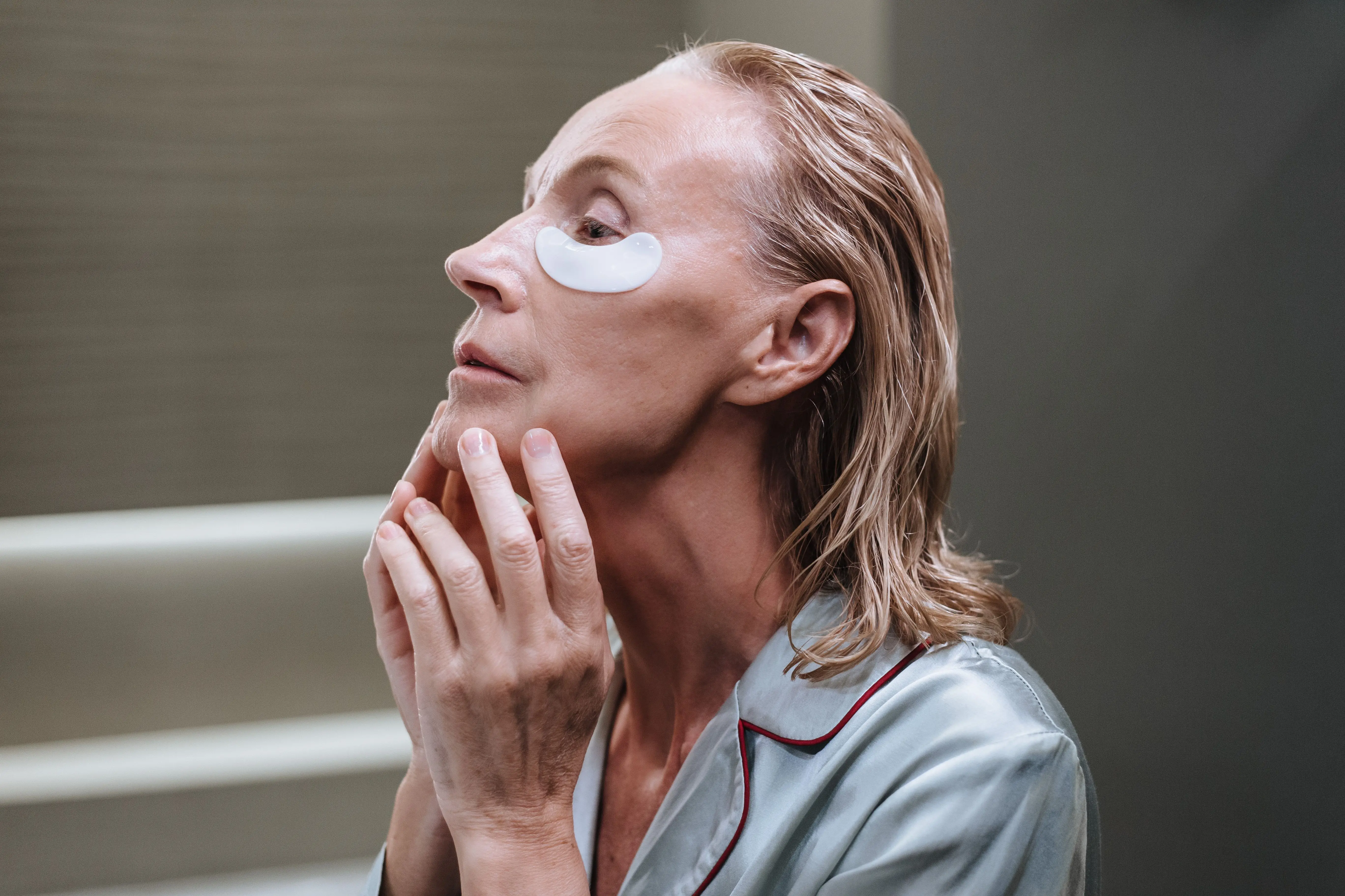 A woman applying under-eye patches as part of a skincare routine