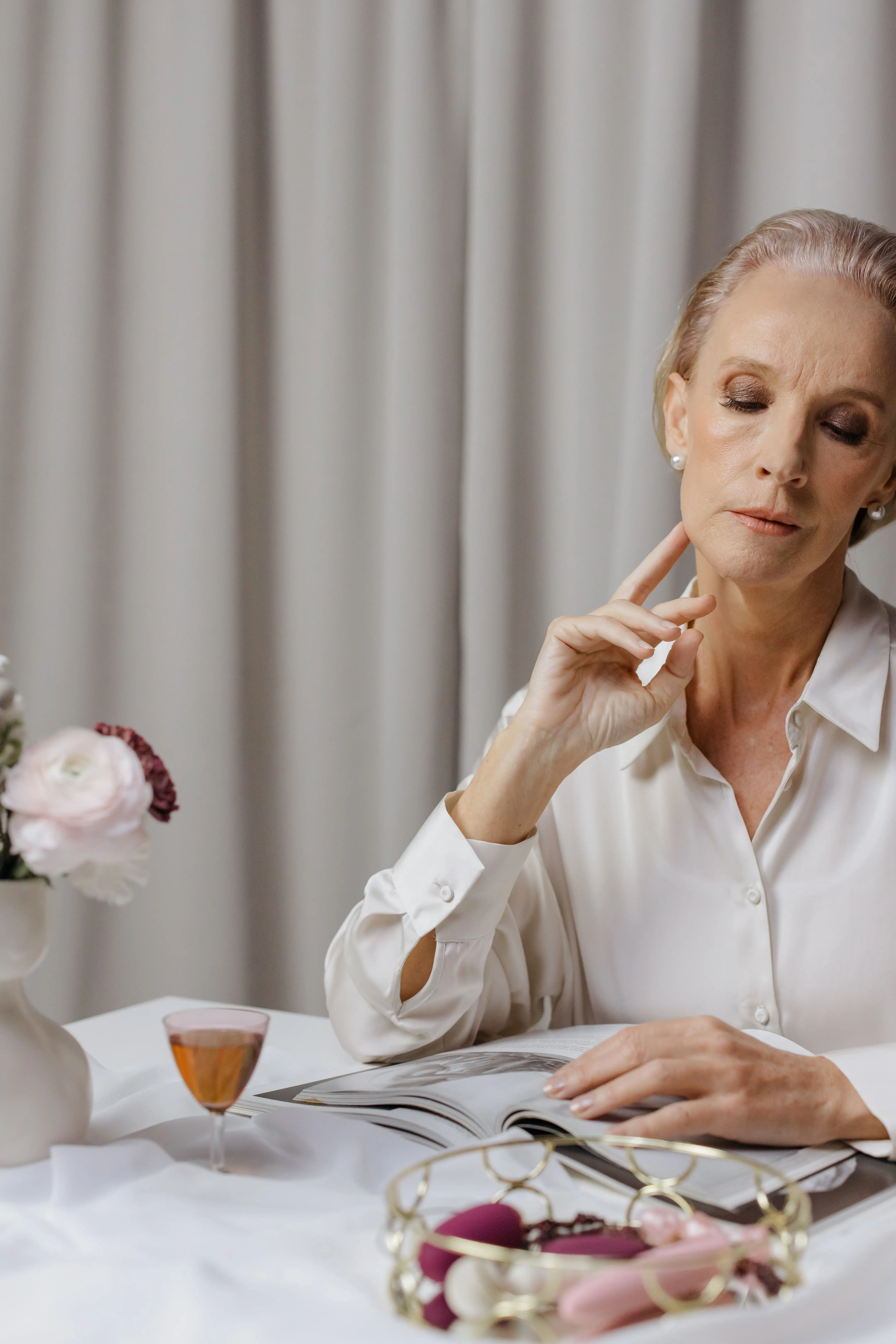 A woman in a white shirt sitting at a table with flowers and a warm drink
